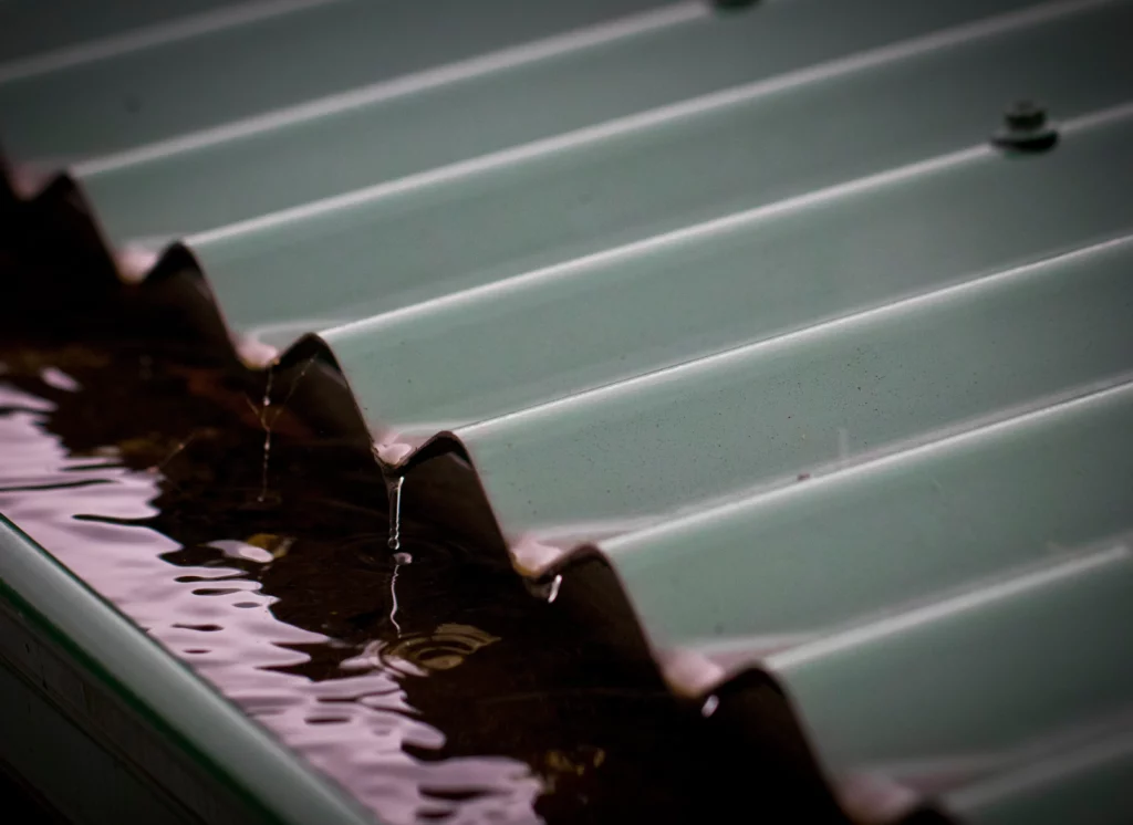 Rain runs over corrugated iron roof into gutter